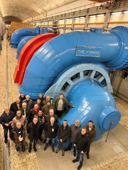 Gruppenfoto vor einer großen blauen Turbine in einem Kraftwerk während einer technischen Exkursion der Bezirksgruppe Garzweiler