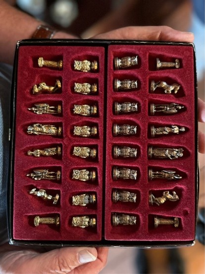 Detailaufnahme eines edlen Schachfiguren-Sets in einer roten Samteinlage, Figuren aus Metall mit historischen oder römischen Motiven
