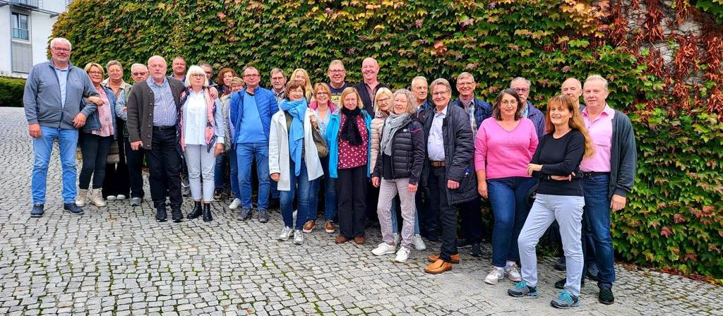 Gruppenfoto der Bezirksgruppe Garzweiler vor einer herbstlich bewachsenen Mauer während einer Vereinsfahrt oder eines Treffens